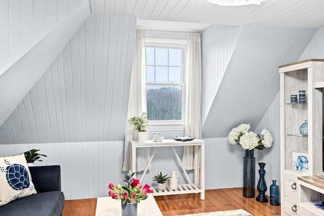 interior space with wood walls, wood finished floors, and vaulted ceiling