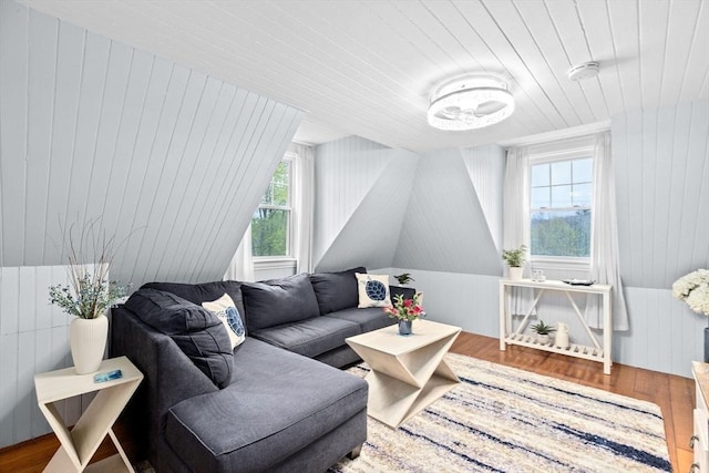 living area with wooden walls, wooden ceiling, and wood finished floors