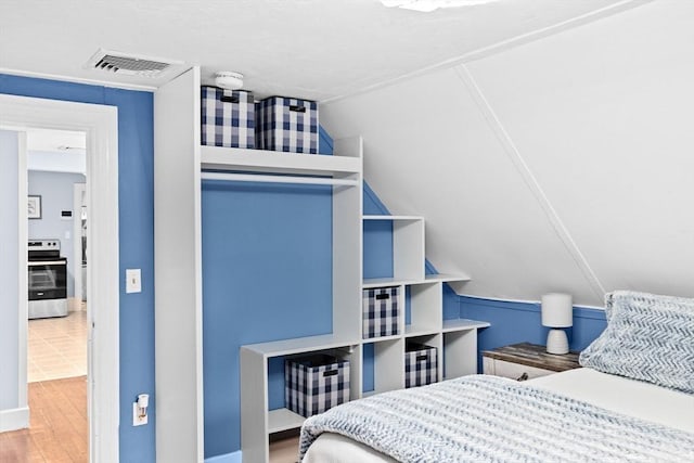 bedroom with visible vents, wood finished floors, and vaulted ceiling