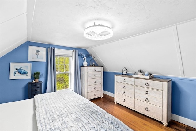bedroom featuring a textured ceiling, dark wood finished floors, and vaulted ceiling