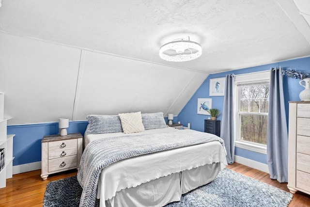bedroom featuring baseboards, lofted ceiling, and wood finished floors