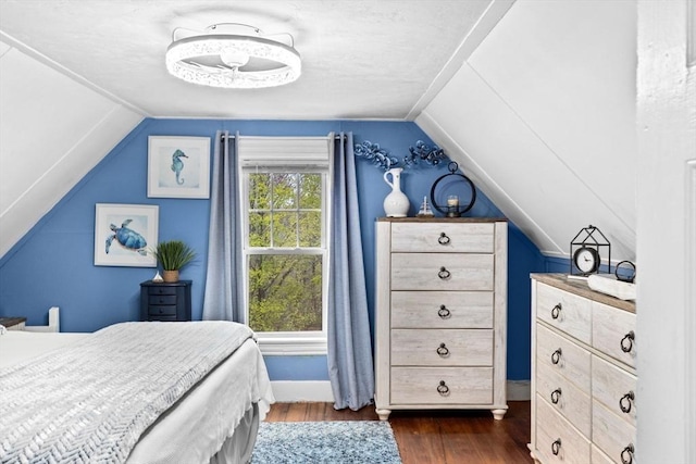 bedroom with baseboards, vaulted ceiling, and dark wood-style flooring