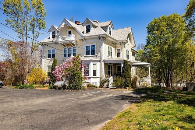 view of front of house with a chimney, a porch, and uncovered parking