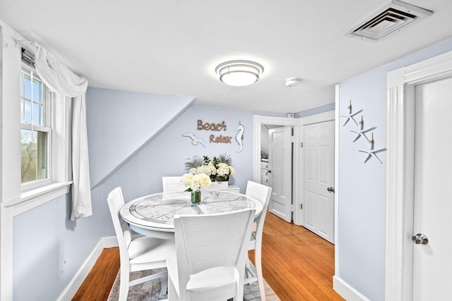 dining area with light wood-style floors, baseboards, and visible vents