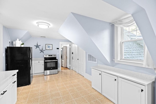 kitchen featuring light countertops, visible vents, freestanding refrigerator, and electric stove