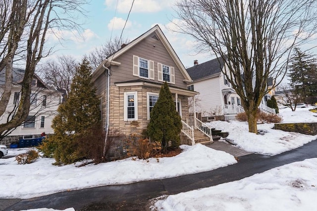 view of snowy exterior featuring stone siding