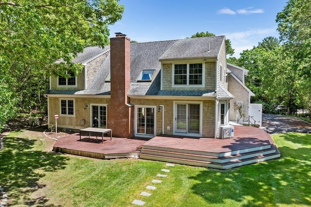 rear view of house with a yard, a chimney, a wooden deck, and roof with shingles