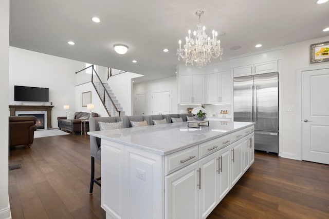 kitchen with dark hardwood / wood-style flooring, white cabinetry, built in refrigerator, and a kitchen island