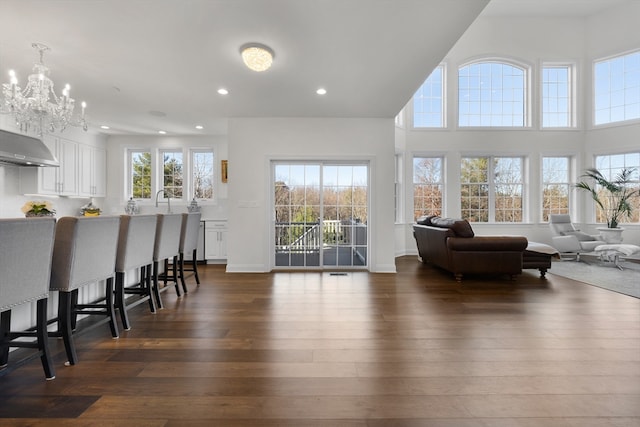 living room with a notable chandelier, dark wood-type flooring, and sink