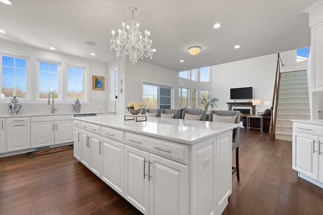 kitchen featuring a breakfast bar area, dark hardwood / wood-style flooring, white cabinetry, and a center island