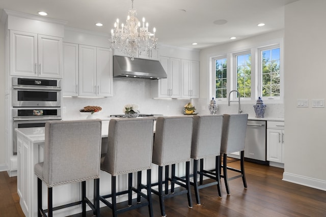 kitchen with a breakfast bar, stainless steel appliances, white cabinets, a center island, and dark hardwood / wood-style floors