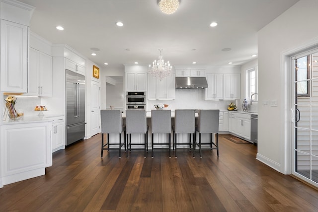 kitchen featuring stainless steel appliances, a kitchen island, dark hardwood / wood-style flooring, extractor fan, and white cabinets