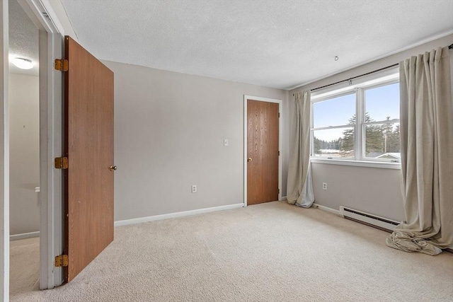 spare room with a baseboard radiator, baseboards, a textured ceiling, and light colored carpet