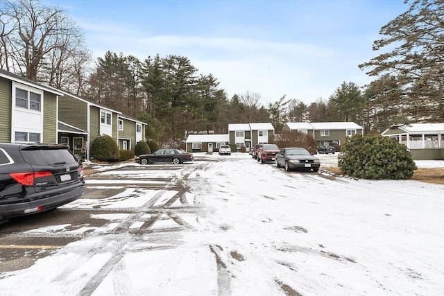 snow covered parking featuring a residential view