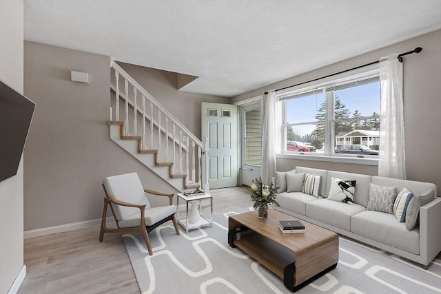 living room with light wood-style floors, stairs, and baseboards