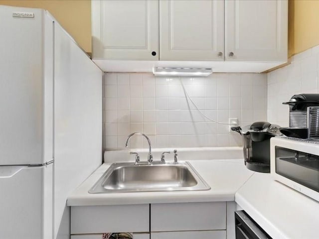 kitchen featuring backsplash, sink, white refrigerator, dishwasher, and white cabinets