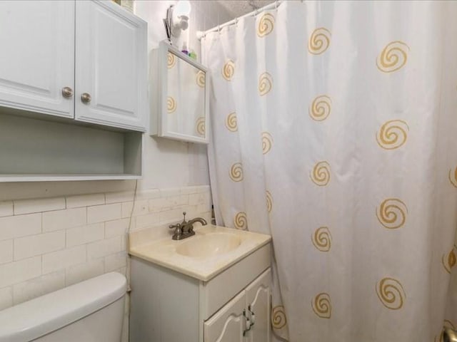 bathroom featuring vanity, tile walls, and toilet