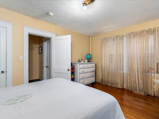 bedroom with a textured ceiling and dark wood-type flooring