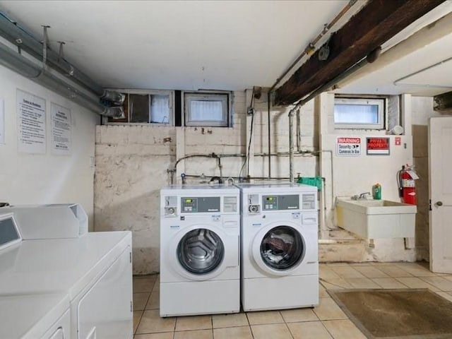 laundry area with light tile patterned flooring, sink, and washing machine and clothes dryer