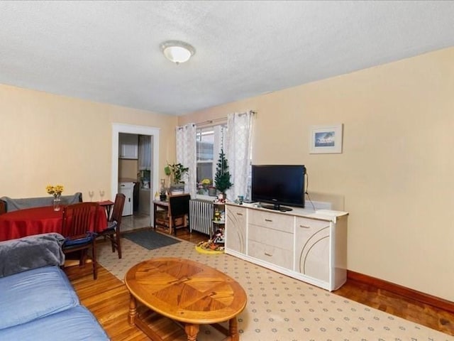 living room featuring independent washer and dryer, a textured ceiling, light hardwood / wood-style floors, and radiator