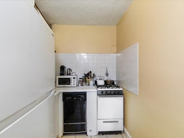 kitchen featuring a textured ceiling, tasteful backsplash, light tile patterned flooring, and white appliances