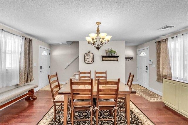 dining space with an inviting chandelier, stairs, visible vents, and wood finished floors