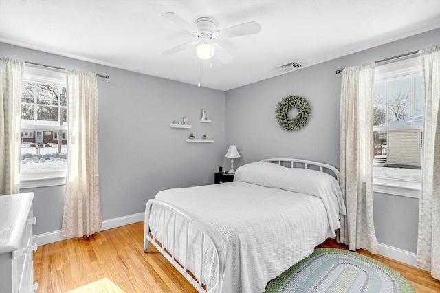 bedroom with multiple windows, light wood-type flooring, visible vents, and baseboards