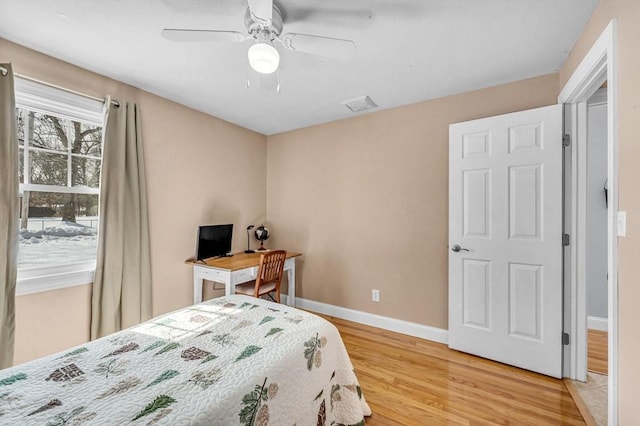 bedroom with baseboards, visible vents, ceiling fan, and wood finished floors