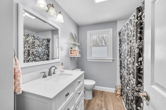 full bath with toilet, wood finished floors, vanity, and baseboards