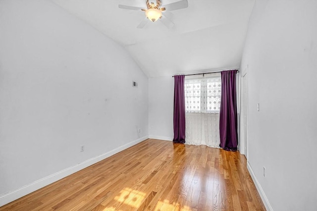 unfurnished room featuring lofted ceiling, baseboards, ceiling fan, and light wood finished floors