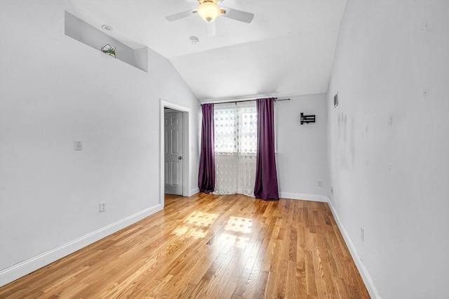 spare room featuring lofted ceiling, light wood-style flooring, baseboards, and ceiling fan