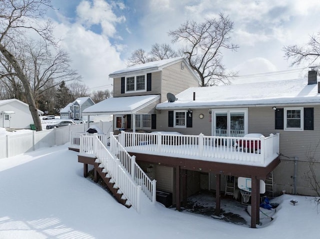 snow covered property featuring a deck, stairway, and fence