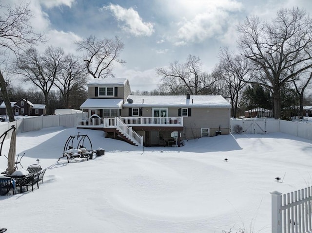 snow covered property featuring a gate, fence, and stairway