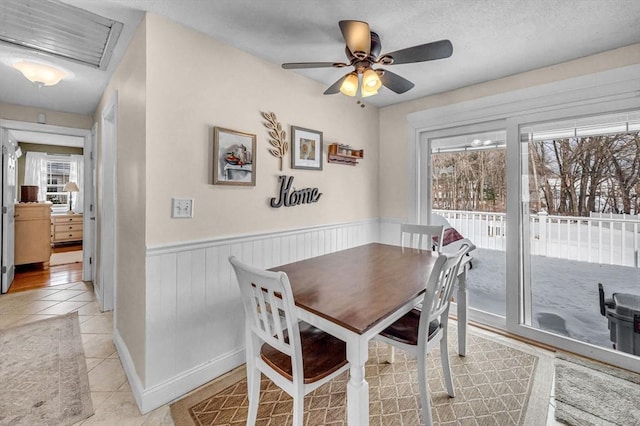 dining area with wainscoting, ceiling fan, and light tile patterned flooring