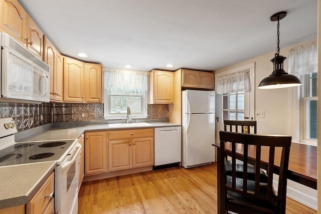 kitchen featuring light hardwood / wood-style flooring, hanging light fixtures, sink, white appliances, and decorative backsplash