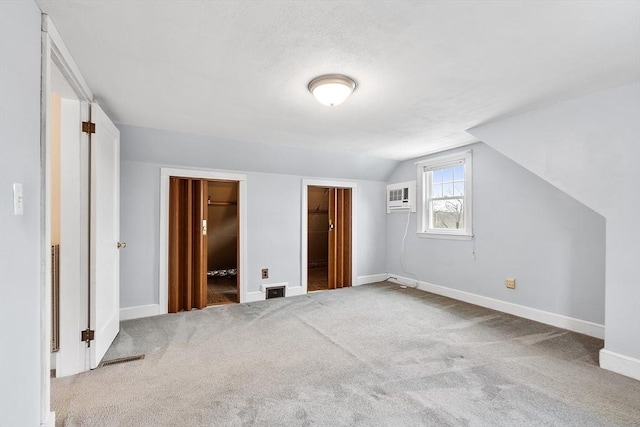 additional living space with carpet floors, a wall unit AC, and lofted ceiling