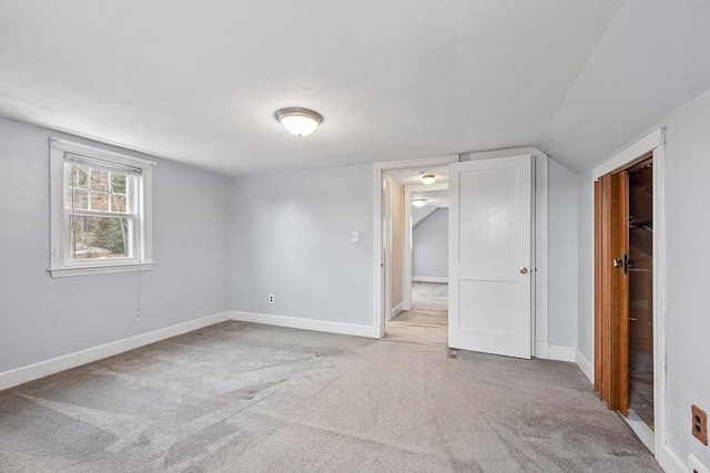 carpeted empty room with vaulted ceiling