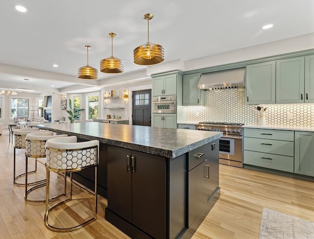 34 Walker St, Somerville, MA 02144 - kitchen with stainless steel appliances, wall chimney range hood, green cabinets, a center island, and recessed lighting