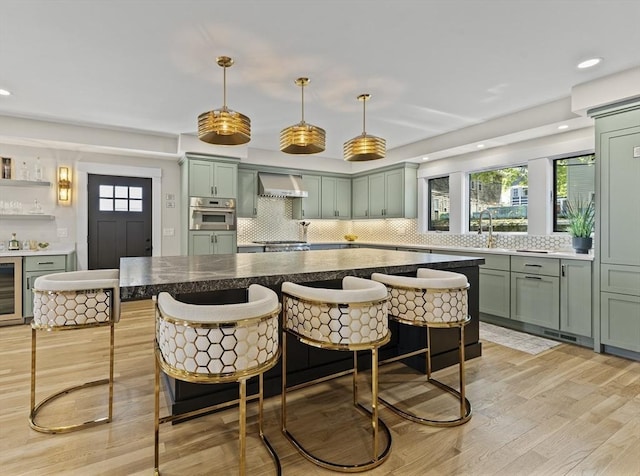 34 Walker St, Somerville, MA 02144 - kitchen with green cabinets, beverage cooler, wall chimney exhaust hood, backsplash, and recessed lighting