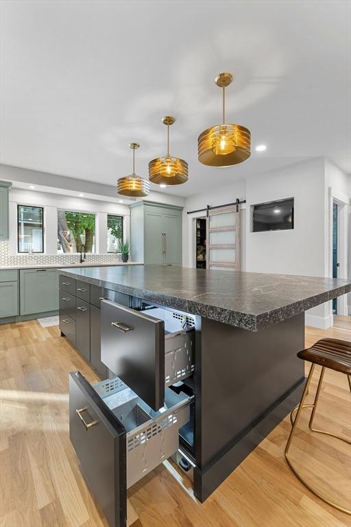 34 Walker St, Somerville, MA 02144 - kitchen featuring a barn door, light wood-style flooring, dark countertops, hanging light fixtures, and recessed lighting