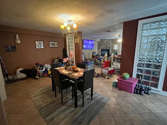 dining area with a notable chandelier, tile patterned flooring, and a fireplace