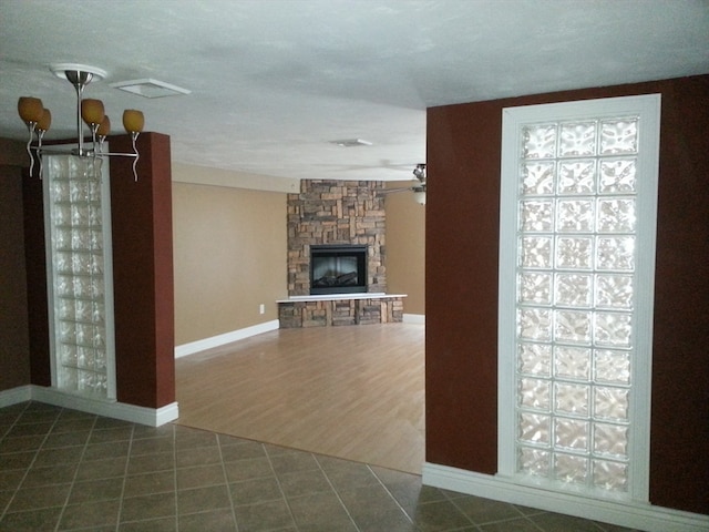 unfurnished living room with ceiling fan with notable chandelier, a fireplace, and dark hardwood / wood-style flooring