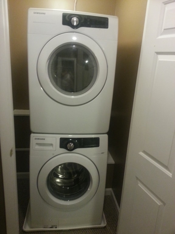 laundry area featuring tile patterned floors and stacked washing maching and dryer