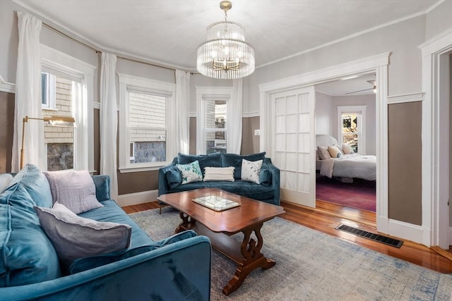 living room with crown molding, an inviting chandelier, and hardwood / wood-style floors