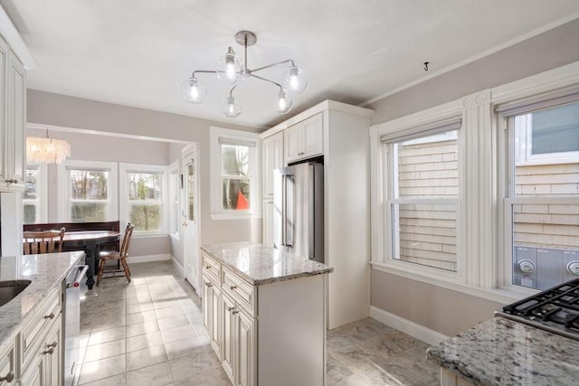 kitchen with decorative light fixtures, appliances with stainless steel finishes, a notable chandelier, and light stone countertops