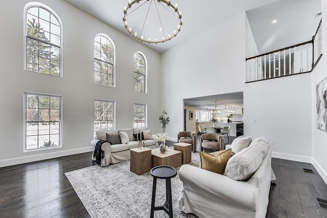 living room featuring a chandelier, dark wood finished floors, and baseboards