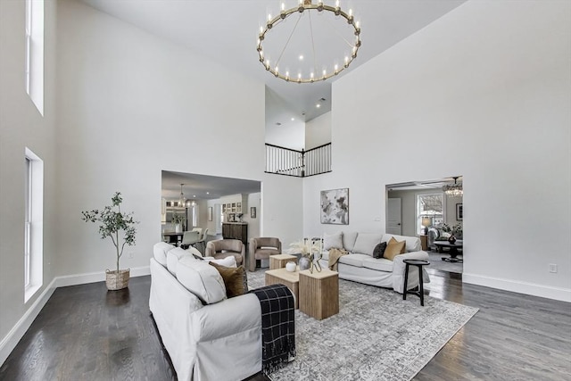 living area featuring an inviting chandelier, baseboards, and dark wood-style flooring