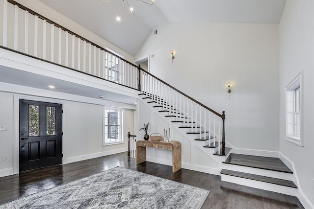 foyer featuring a notable chandelier, dark wood finished floors, stairway, high vaulted ceiling, and baseboards