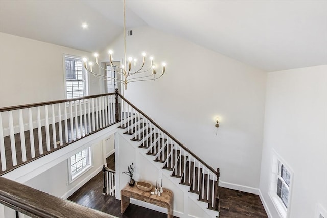 stairway featuring baseboards, high vaulted ceiling, wood finished floors, and an inviting chandelier