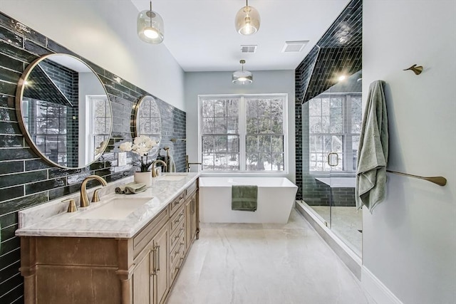 full bath featuring double vanity, visible vents, a freestanding bath, a shower stall, and a sink